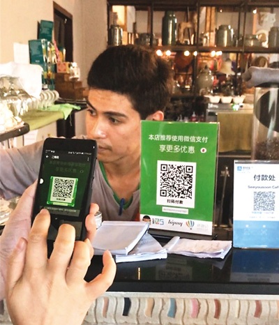 4月18日，在泰国清迈一家酒吧，顾客通过微信扫码支付。(新华社发)